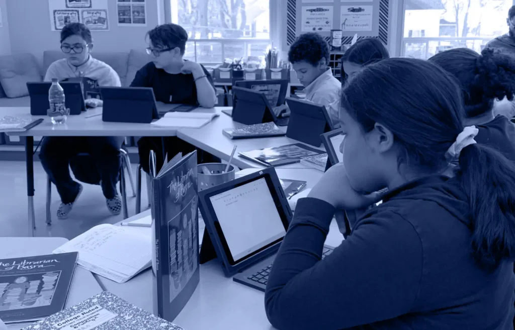 Kids studying on tablets at their desks.